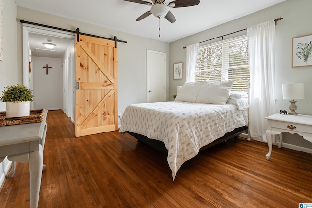 bedroom featuring a barn door, ceiling fan, baseboards, and dark wood-style flooring