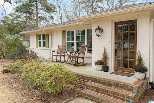 entrance to property with brick siding, a porch, and board and batten siding