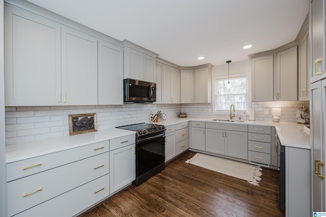 kitchen featuring tasteful backsplash, stainless steel microwave, dark wood finished floors, electric stove, and a sink