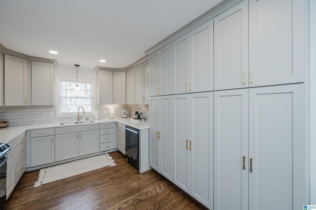 kitchen featuring electric range, dark wood-style flooring, a sink, light countertops, and tasteful backsplash