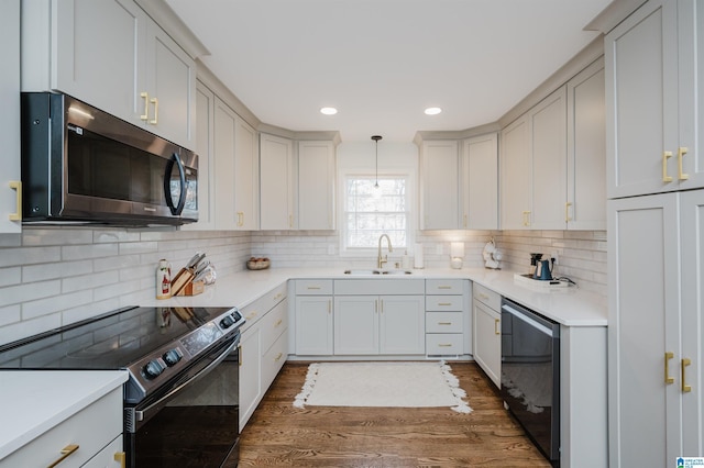 kitchen featuring stainless steel microwave, backsplash, dark wood-type flooring, black / electric stove, and a sink