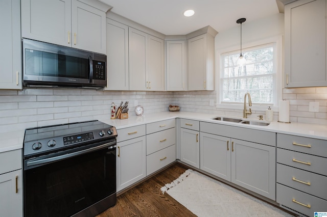 kitchen with a sink, backsplash, electric range oven, light countertops, and dark wood-style flooring