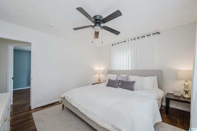 bedroom featuring a ceiling fan, visible vents, dark wood-style flooring, and baseboards