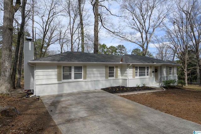 ranch-style house with concrete driveway, brick siding, and a chimney