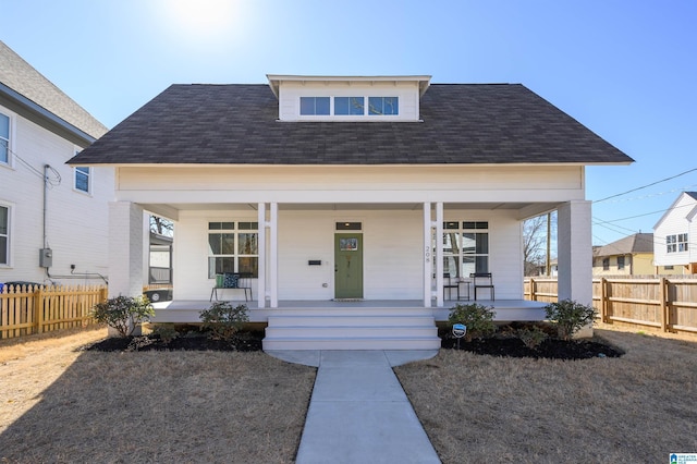 bungalow-style house featuring fence, covered porch, and a shingled roof