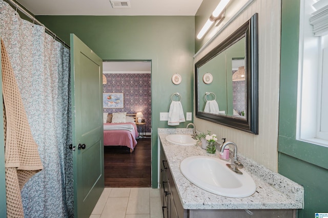 ensuite bathroom with a sink, ensuite bath, double vanity, and tile patterned flooring