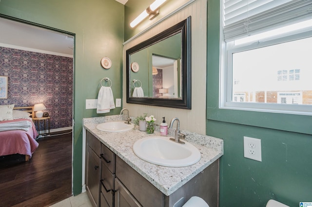 full bathroom featuring double vanity, ensuite bathroom, baseboards, and a sink