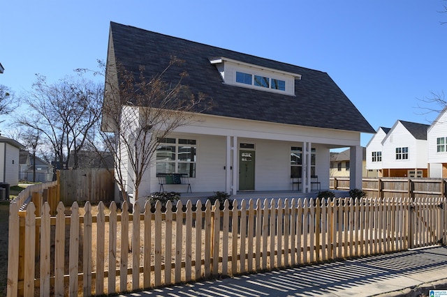 view of front of property with a fenced front yard, a porch, and roof with shingles