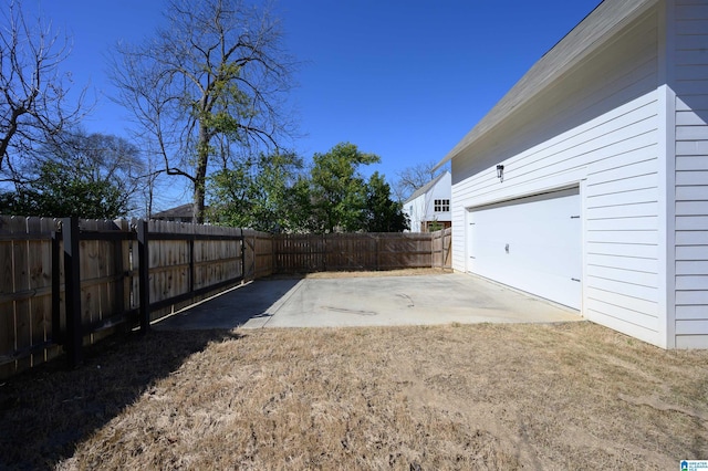 view of yard featuring a fenced backyard, a garage, and driveway