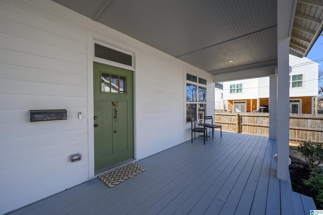 wooden terrace featuring covered porch and fence