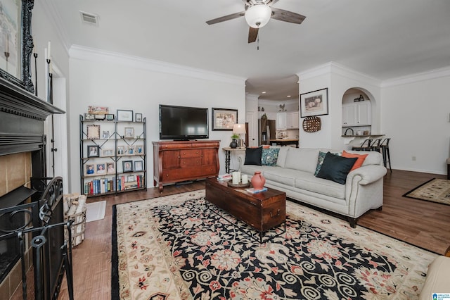 living area with visible vents, ornamental molding, ceiling fan, and wood finished floors