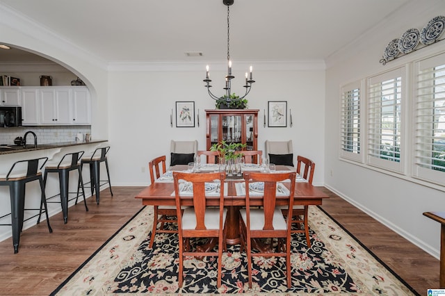 dining space with baseboards, visible vents, dark wood-style flooring, arched walkways, and ornamental molding