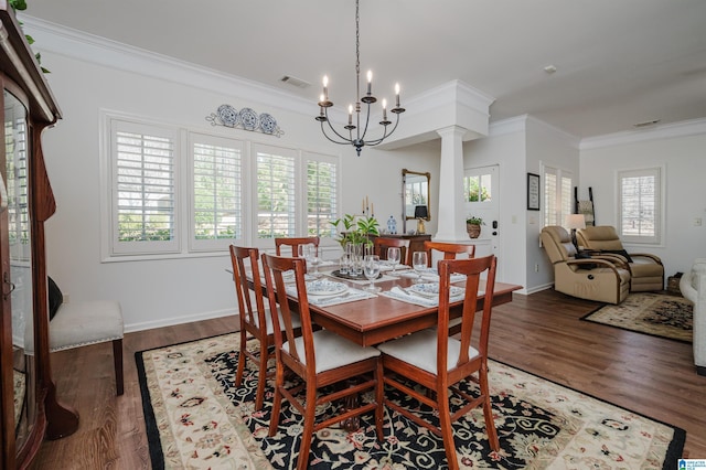 dining space featuring visible vents, crown molding, a chandelier, wood finished floors, and ornate columns