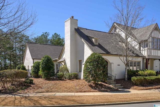 view of home's exterior featuring stucco siding, a chimney, and roof with shingles