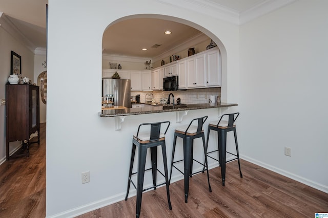 kitchen featuring tasteful backsplash, black microwave, dark stone counters, stainless steel refrigerator with ice dispenser, and white cabinetry