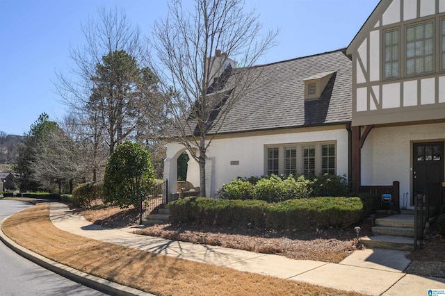 tudor house featuring stucco siding and a shingled roof