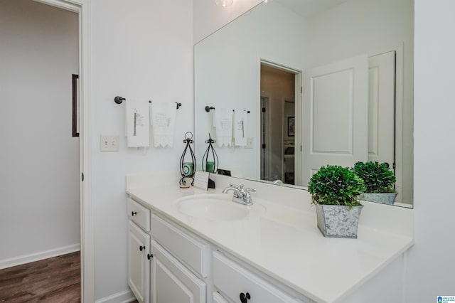 bathroom with vanity, wood finished floors, and baseboards