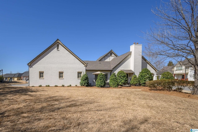 view of home's exterior featuring a yard, brick siding, and a chimney