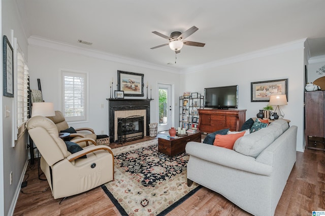 living room with visible vents, crown molding, a tile fireplace, wood finished floors, and a ceiling fan