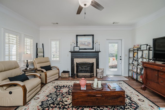 living area featuring wood finished floors, a healthy amount of sunlight, ornamental molding, and a tile fireplace