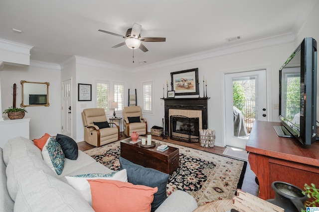 living room featuring visible vents, a tile fireplace, crown molding, and wood finished floors