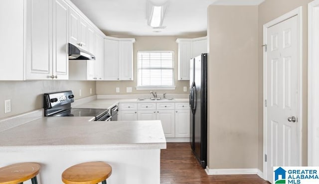 kitchen with a peninsula, freestanding refrigerator, a sink, range with electric cooktop, and under cabinet range hood