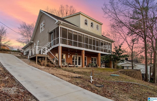 view of front of property with stairway and a sunroom