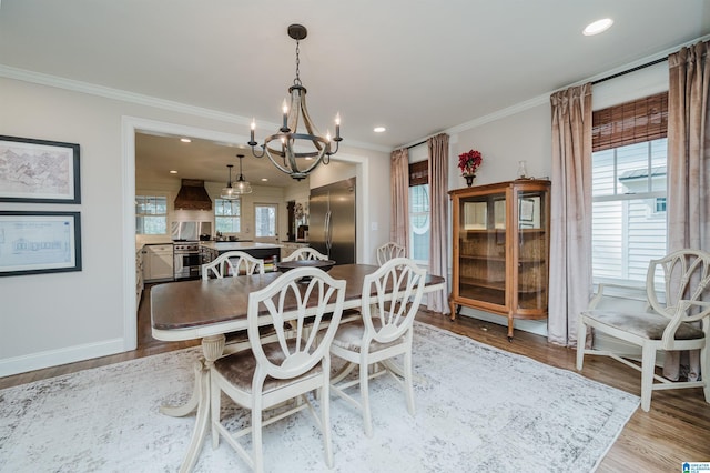 dining area featuring an inviting chandelier, a healthy amount of sunlight, light wood-style floors, and ornamental molding