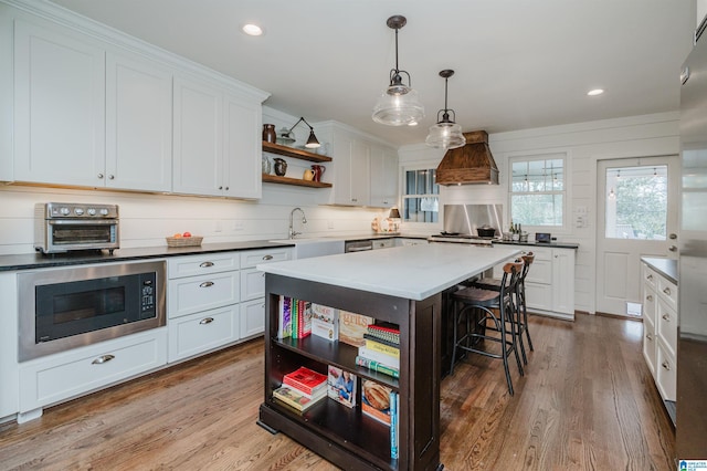 kitchen with built in microwave, a kitchen bar, wood finished floors, custom exhaust hood, and open shelves