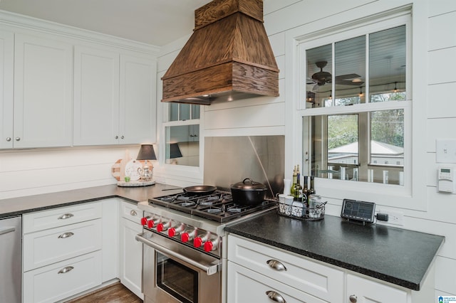 kitchen with premium range hood, ceiling fan, white cabinets, appliances with stainless steel finishes, and dark countertops