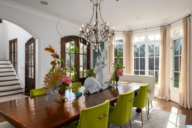 dining area featuring a wealth of natural light, arched walkways, a notable chandelier, and wood finished floors