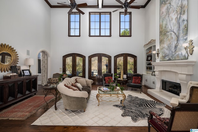 living room featuring wood finished floors, arched walkways, french doors, and ceiling fan