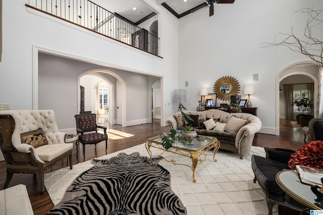 living room with arched walkways, a ceiling fan, and wood finished floors