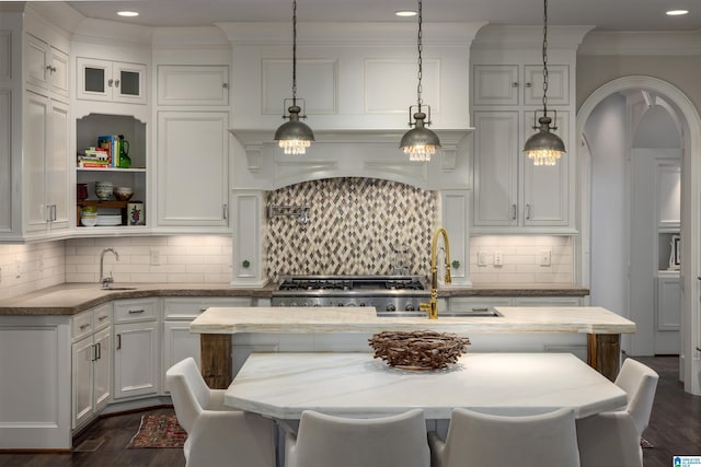 kitchen with white cabinetry, crown molding, dark wood-style flooring, and backsplash