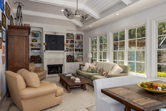 living room with beamed ceiling, a healthy amount of sunlight, and a large fireplace