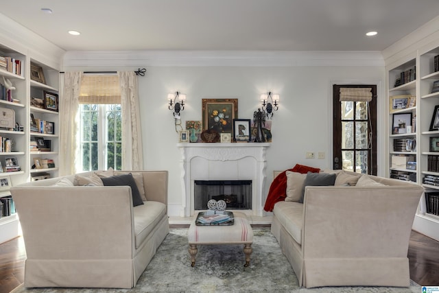 living area with ornamental molding, built in features, wood finished floors, recessed lighting, and a fireplace