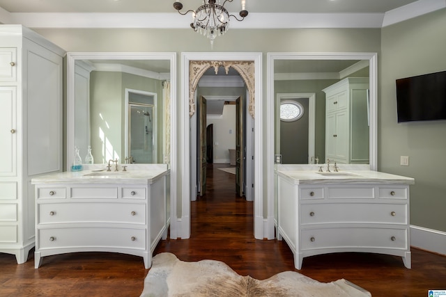 bathroom with a sink, a chandelier, two vanities, and wood finished floors