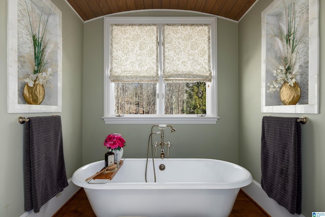 bathroom with lofted ceiling, a freestanding tub, and baseboards