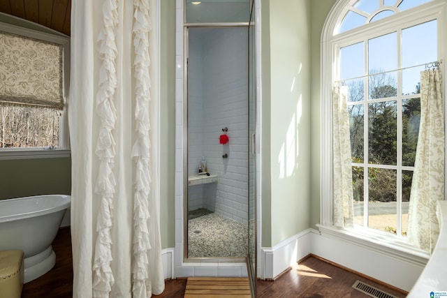 bathroom with visible vents, a stall shower, wood finished floors, baseboards, and a soaking tub