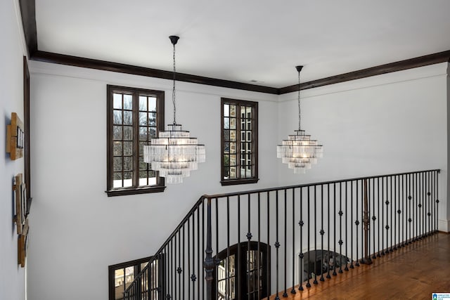 stairway featuring crown molding, a notable chandelier, and wood finished floors