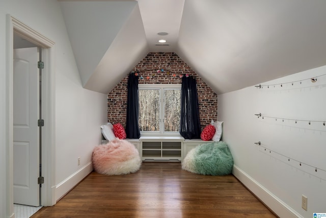 additional living space with vaulted ceiling, brick wall, baseboards, and wood finished floors