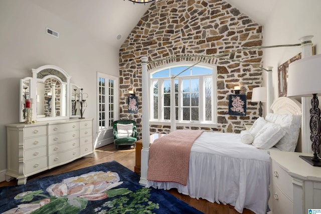 bedroom featuring visible vents, high vaulted ceiling, and wood finished floors