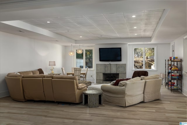 living room with recessed lighting, visible vents, a tiled fireplace, and light wood finished floors