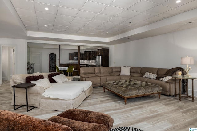 living room featuring recessed lighting, a tray ceiling, a drop ceiling, and light wood finished floors