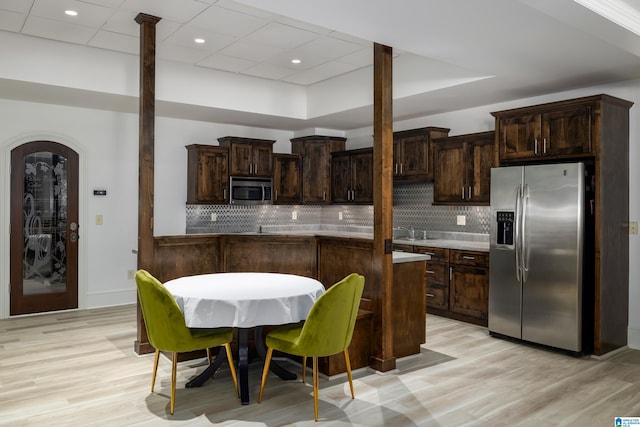 kitchen with light wood-style flooring, a sink, tasteful backsplash, stainless steel appliances, and dark brown cabinets