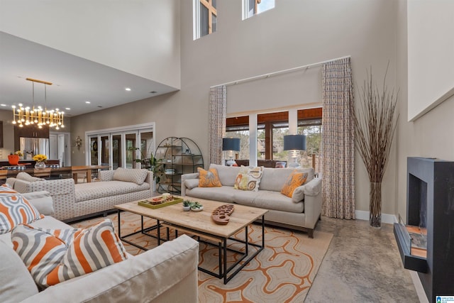 living room featuring baseboards, an inviting chandelier, a high ceiling, recessed lighting, and finished concrete floors