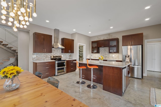 kitchen featuring a center island, stainless steel appliances, concrete floors, wall chimney exhaust hood, and light countertops