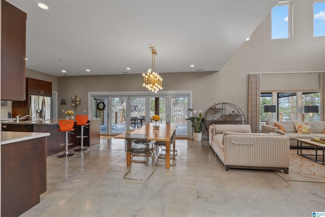 dining room with a towering ceiling, recessed lighting, concrete flooring, and french doors