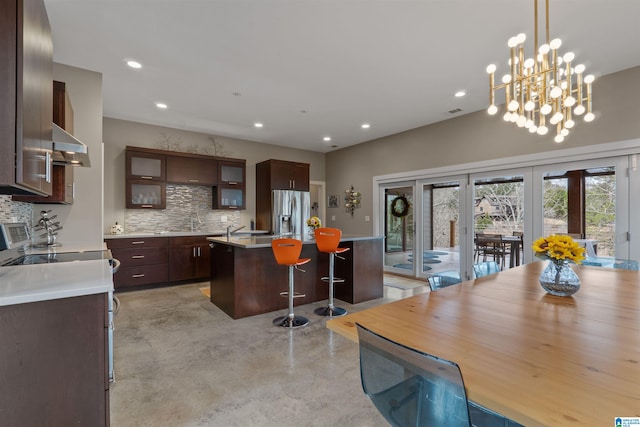 kitchen featuring a center island, stainless steel fridge with ice dispenser, a breakfast bar, concrete flooring, and decorative backsplash