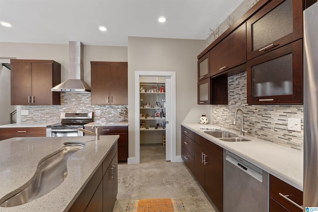 kitchen with wall chimney range hood, light stone countertops, recessed lighting, appliances with stainless steel finishes, and a sink